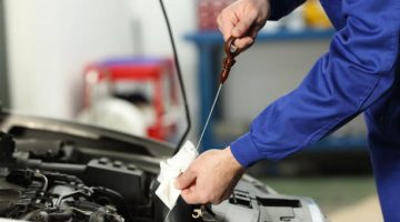 Close up of a car mechanic checking oil level in a mechanical workshop